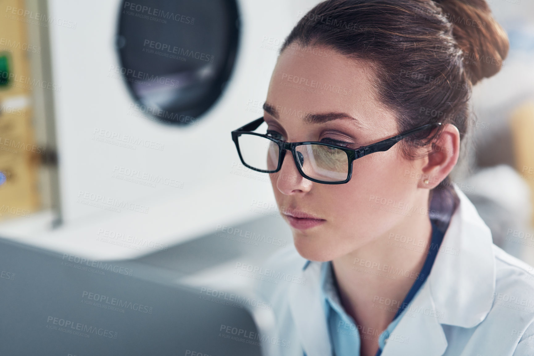 Buy stock photo Cropped shot of a focused young female scientist working on a computer inside of a laboratory during the day