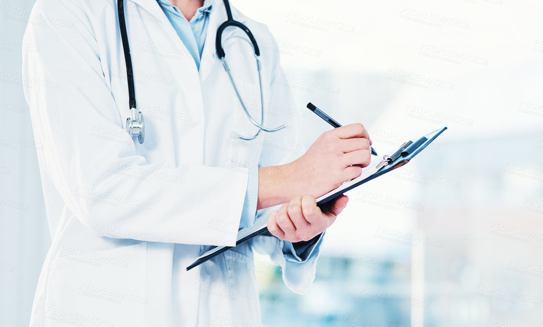 Buy stock photo Cropped shot of an unrecognizable doctor making notes on a clipboard inside of a hospital