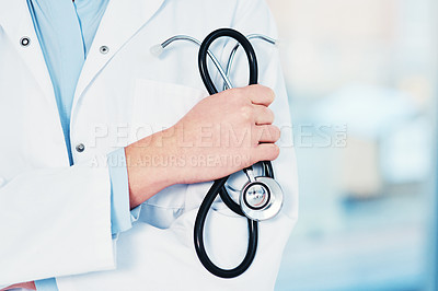 Buy stock photo Cropped shot of an unrecognizable doctor holding a stethoscope in their hand while standing inside of a hospital during the day