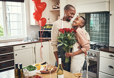 Buy stock photo Flowers, love and valentines day with a black couple in the kitchen for a romantic celebration together. Food, gift or romance with a man and woman bonding in their home during a special event