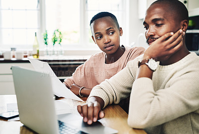Buy stock photo Shot of a young couple looking stressed while going over their finances on a laptop at home