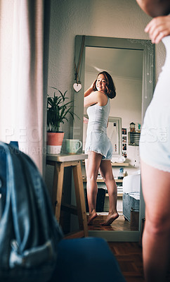 Buy stock photo Shot of an attractive young woman admiring her body while standing in font of the mirror in her bedroom at home
