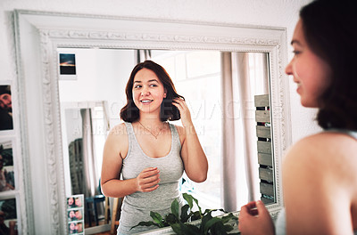 Buy stock photo Cropped shot of an attractive young woman admiring herself while standing in front of the mirror in her bedroom at home