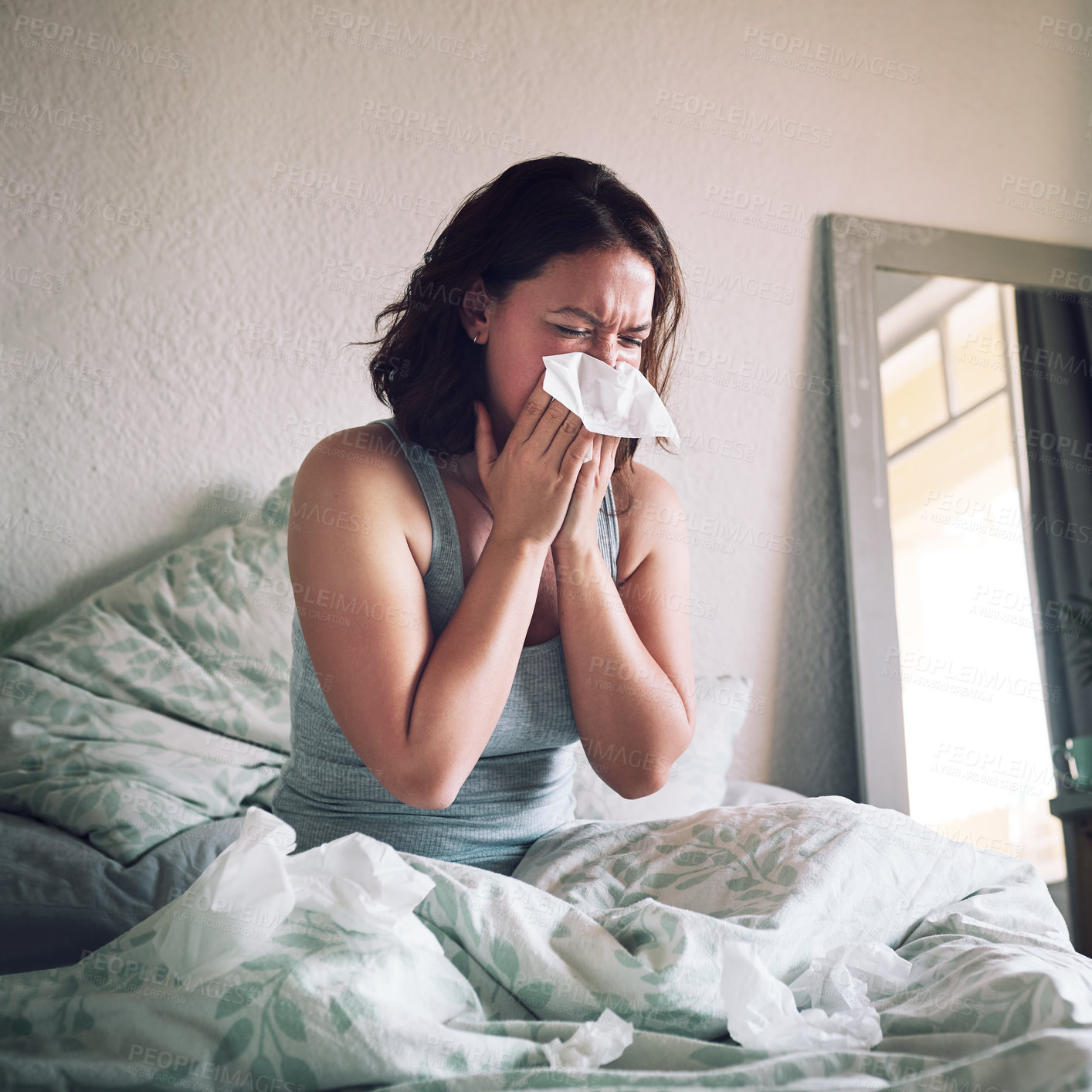 Buy stock photo Shot of an attractive young woman suffering with the flu while sitting on her bed at home