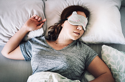 Buy stock photo High angle shot of an attractive young woman sleeping with a mask on her face in her bedroom at home