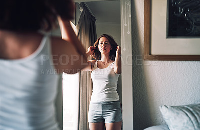 Buy stock photo Cropped shot of an attractive young woman inspecting her hair while standing in front of the mirror in her bedroom at home