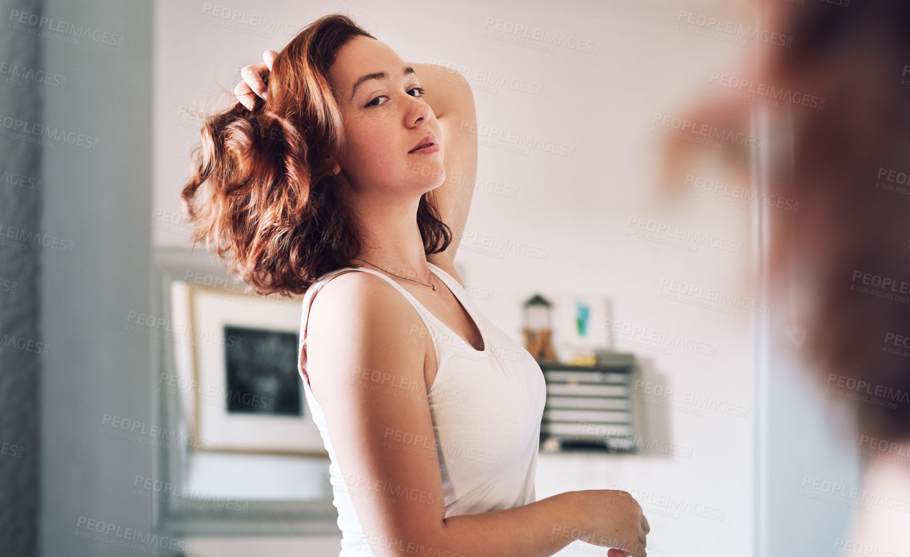 Buy stock photo Cropped shot of an attractive young woman inspecting herself while standing in front of the mirror in her bedroom at home