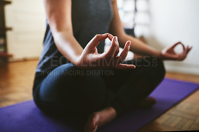 Buy stock photo Cropped shot of an unrecognizable woman sitting on a yoga mat and meditating alone in her home