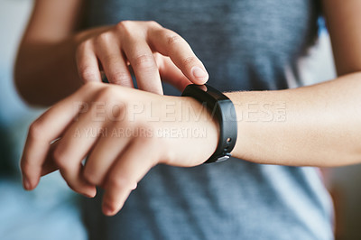 Buy stock photo Cropped shot of an unrecognizable woman standing alone in her home and setting her fitness tracker before working out