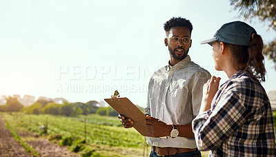 Buy stock photo Cropped shot of two young farmers looking over some paperwork while working on their farm