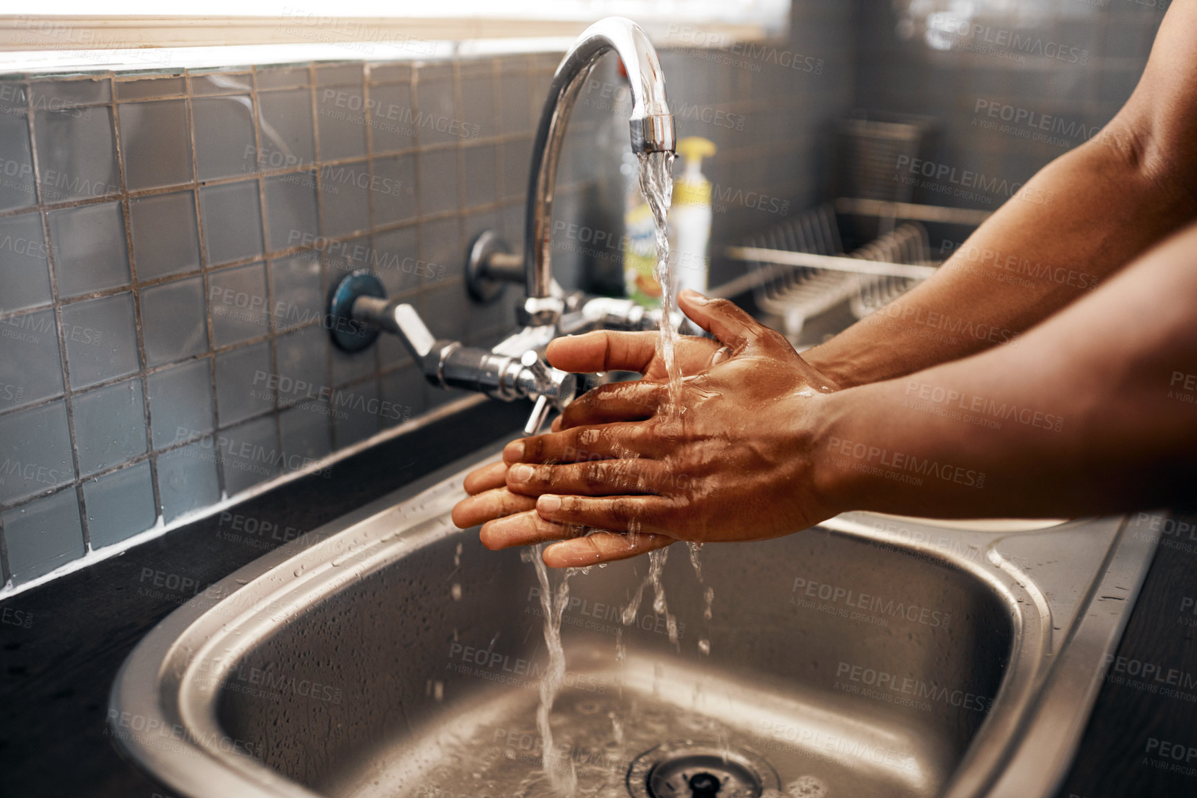Buy stock photo Cropped shot of an unrecognizable man washing his hands in the kitchen sink at home