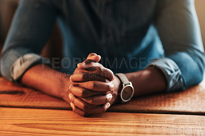 Buy stock photo Quiet, calm and spiritual man praying while sitting with his hands folded alone at home. Close up praying, hopeful and religious, Christian male saying a daily prayer in the morning at a table