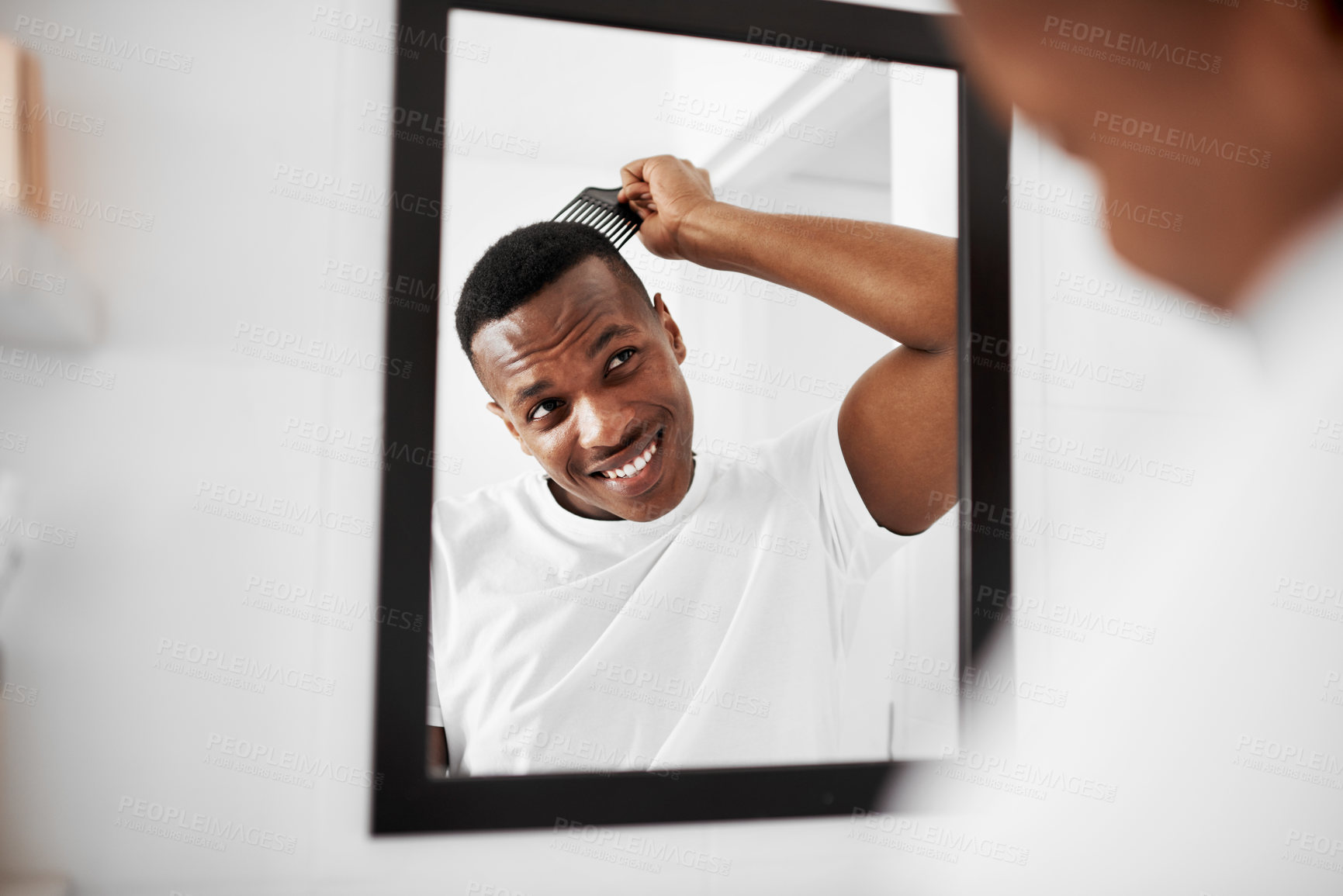 Buy stock photo Shot of a handsome young man combing his hair in the bathroom at home