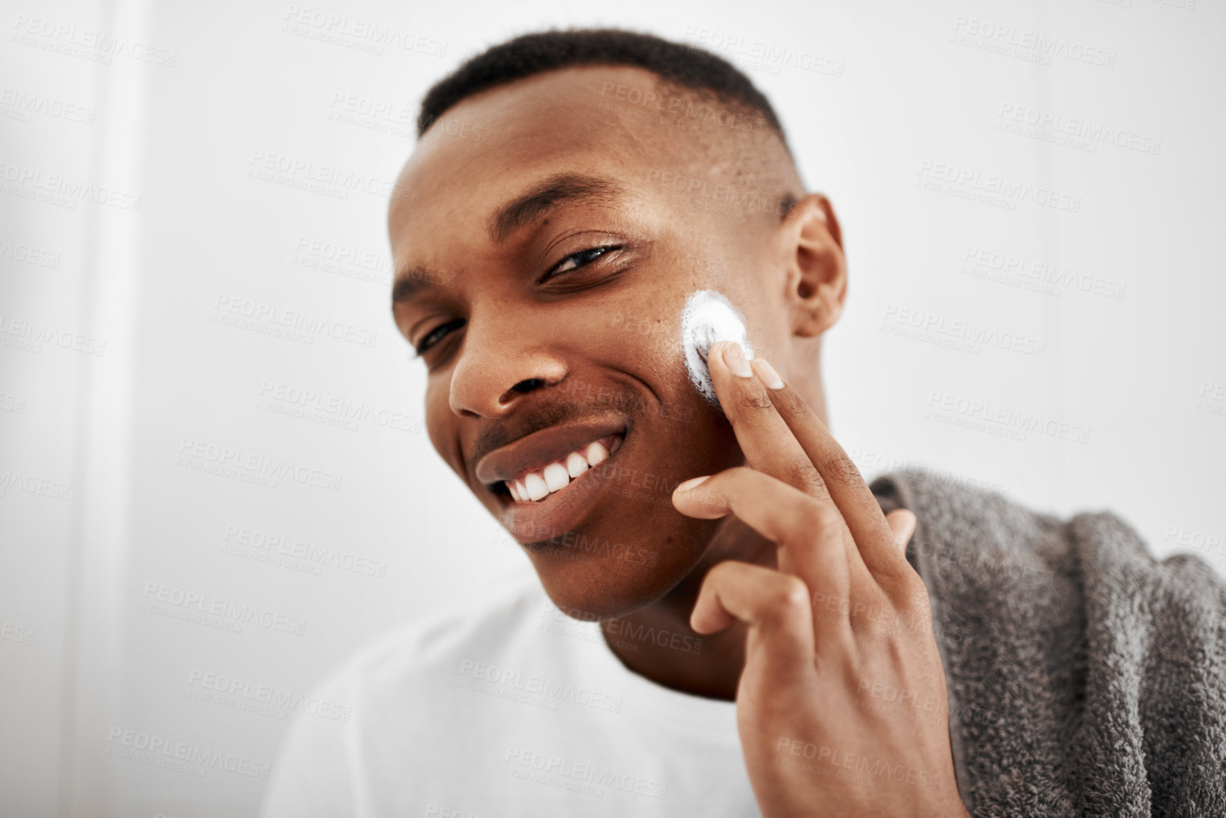 Buy stock photo Happy, portrait and black man with lotion for skincare, moisturizer or cosmetics in bathroom. Face, young African or male person with smile for soft skin, SPF or facial cream in morning routine