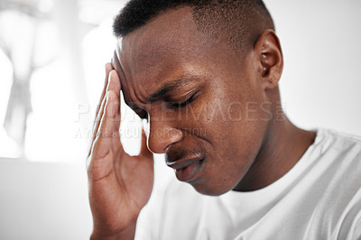 Buy stock photo Cropped shot of a young man suffering from a headache at home