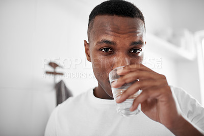 Buy stock photo Cropped shot of a young man drinking a glass of water at home