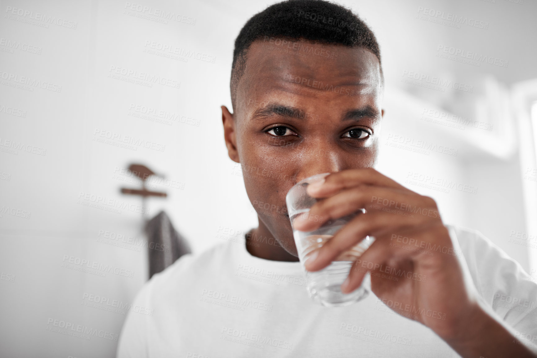 Buy stock photo Cropped shot of a young man drinking a glass of water at home