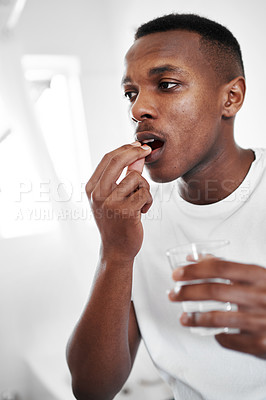 Buy stock photo Cropped shot of a young man taking medication at home