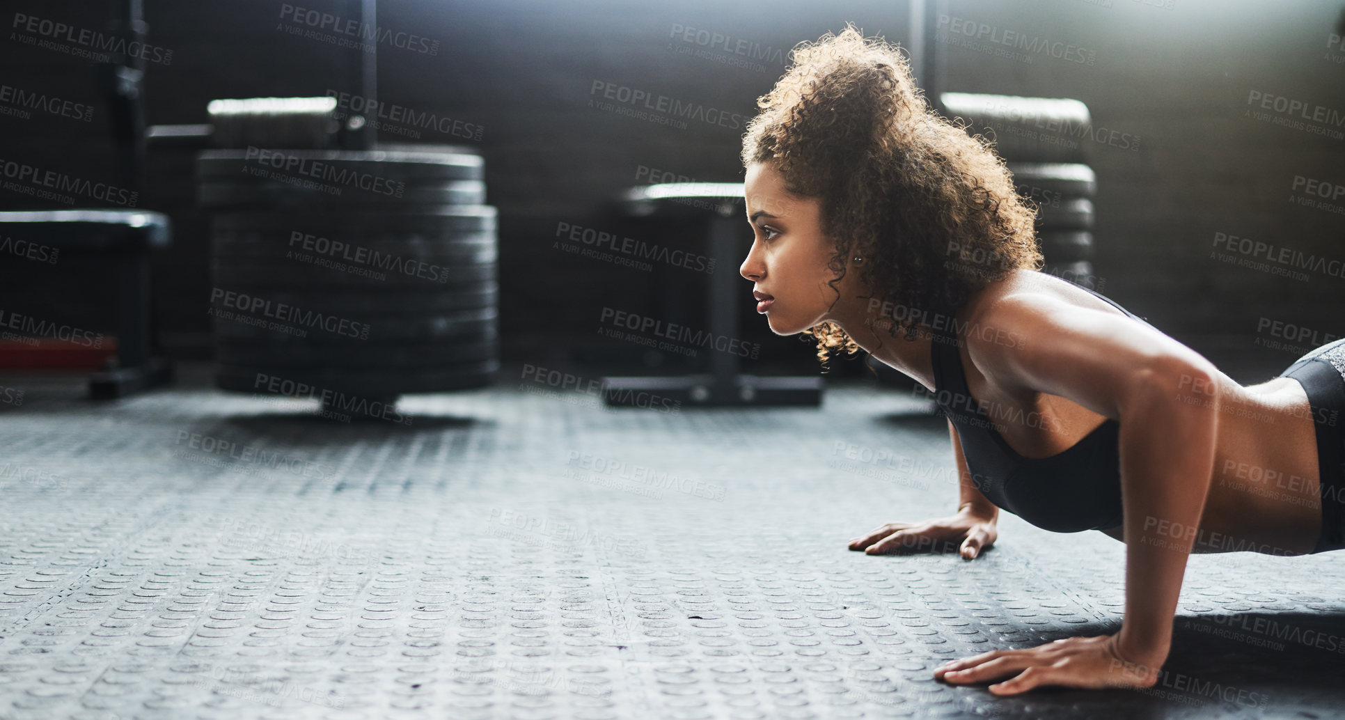 Buy stock photo Shot of a young woman doing pushups in a gym