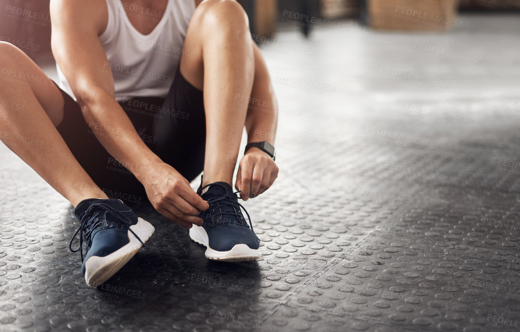 Buy stock photo Cropped shot of a man tying his shoelaces in a gym