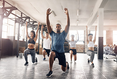 Buy stock photo Shot of a group of young people doing lunges together during their workout in a gym