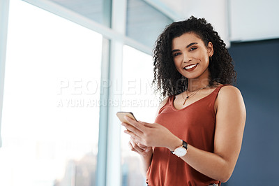 Buy stock photo Cropped portrait of an attractive young businesswoman standing alone in her office and texting on her cellphone