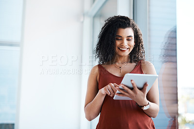 Buy stock photo Cropped shot of an attractive young businesswoman standing alone in her office and using a tablet