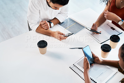 Buy stock photo High angle shot of an unrecognizable group of businesspeople sitting in the office together and texting on their cellphones