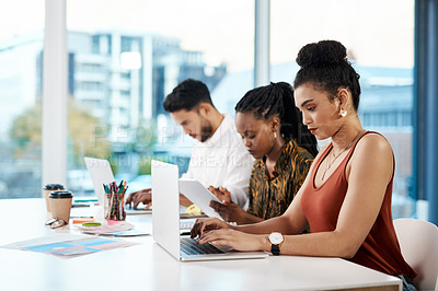 Buy stock photo Cropped shot of a diverse group of businesspeople sitting in the office together and working on technology