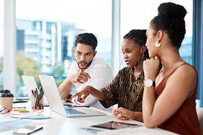 Buy stock photo Cropped shot of a diverse group of businesspeople sitting in the office together and looking at a laptop