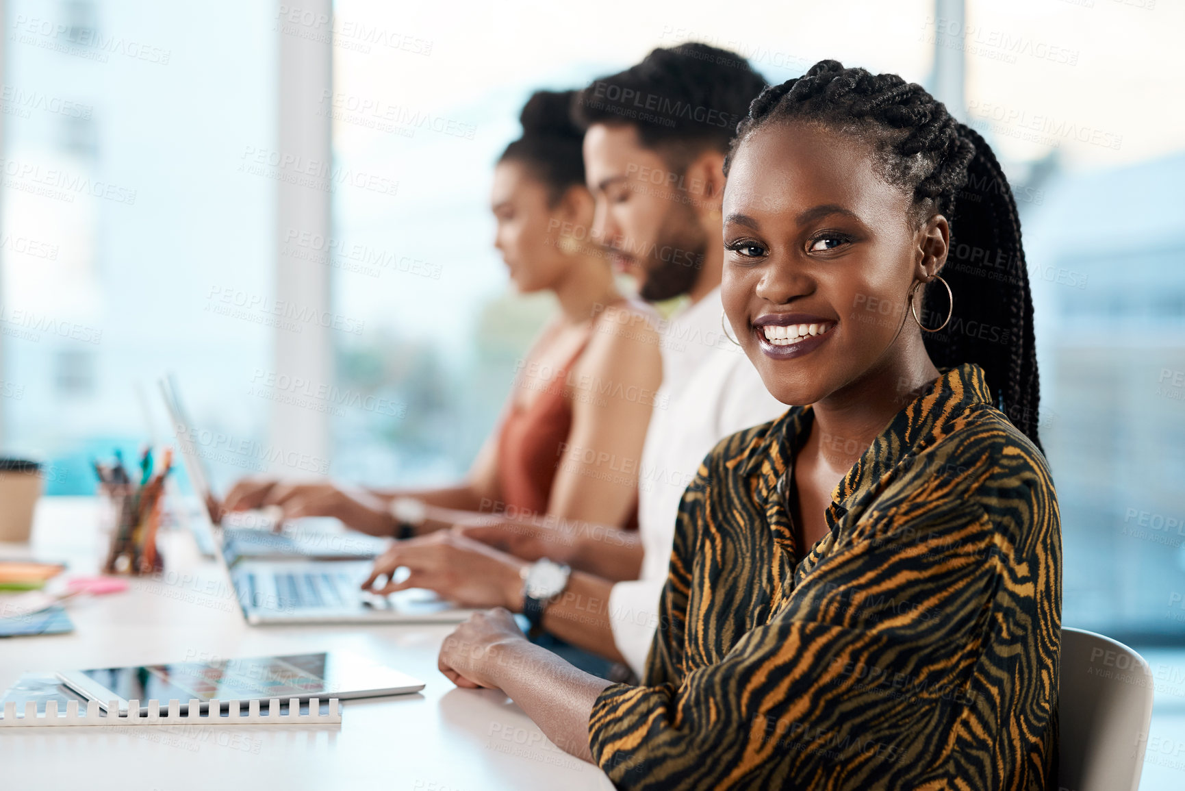 Buy stock photo Cropped portrait of an attractive young businesswoman sitting in the office while her colleagues work on laptops behind her