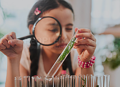 Buy stock photo Cropped shot of an adorable little girl looking through a magnifying glass while analysing plants from a test tube at home
