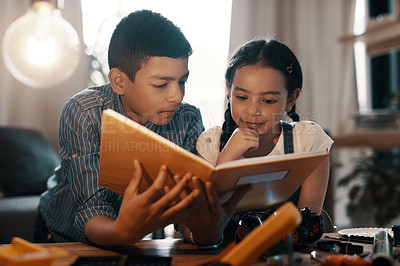 Buy stock photo Education, children reading a book and in a living room at their home. Research information, knowledge or study and young siblings with textbook learning together as a team with robotics on table