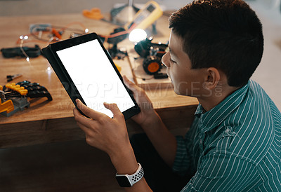 Buy stock photo Shot of a handsome young boy using a digital tablet while trying to build a robotic toy at home