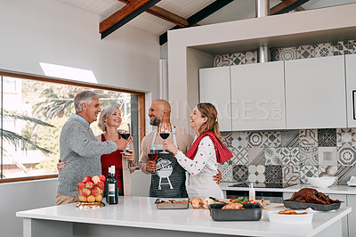 Buy stock photo Shot of a group of mature friends toasting with wine while preparing a Thanksgiving meal