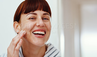 Buy stock photo Cropped portrait of an attractive young woman smiling while  applying sea salt on her face at home