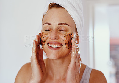 Buy stock photo Cropped shot of an attractive young woman smiling while applying a coffee mask on her face at home