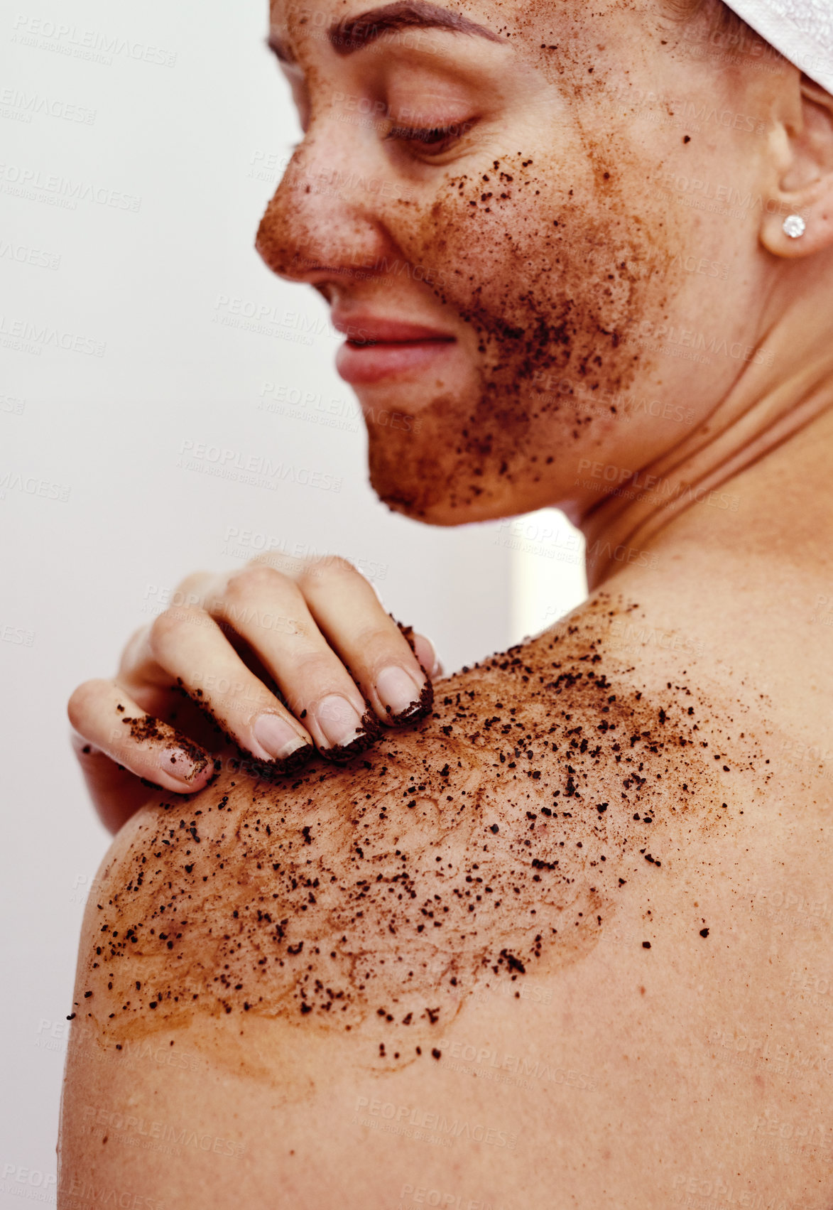 Buy stock photo Cropped shot of an attractive young woman smiling while applying a coffee mask on her body at home