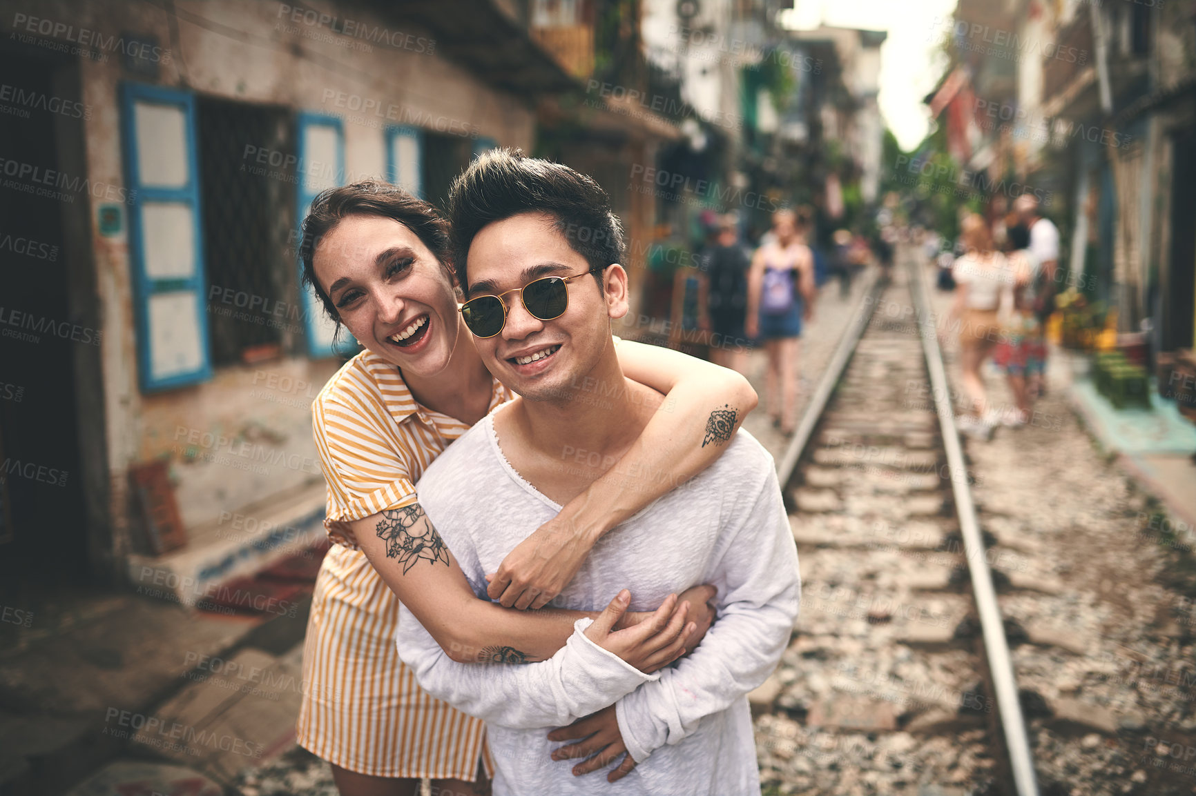 Buy stock photo Shot of a young couple sharing a romantic moment on the train tracks in the streets of Vietnam