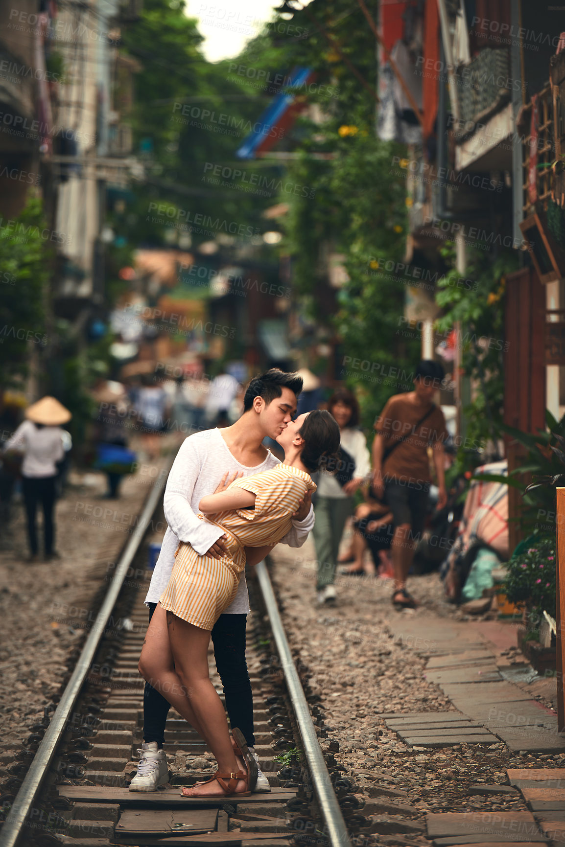 Buy stock photo Kiss, travel and couple on traintracks in Vietnam for holiday, vacation and tourist destination. Honeymoon, love and happy man and woman on railway for adventure, journey and bonding in urban city