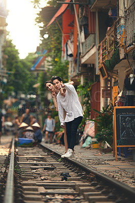 Buy stock photo Interracial couple, travel and sightseeing on train station in city for directions, journey or vacation. Woman, man and pointing on railway on holiday, adventure or outdoor fun by platform in Vietnam