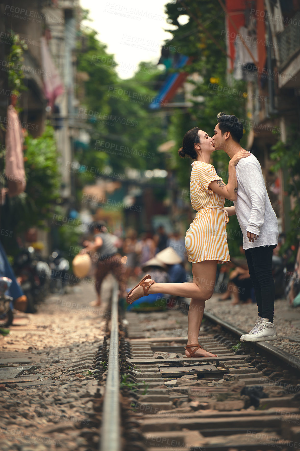 Buy stock photo Kiss, city and couple on train tracks in Vietnam for holiday, vacation and tourist destination. Travel, love and man and woman embrace on railway for adventure, journey and bonding in urban village