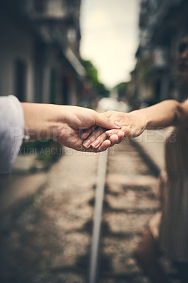 Buy stock photo Cropped shot of a couple holding hands while walking on the train tracks in Vietnam