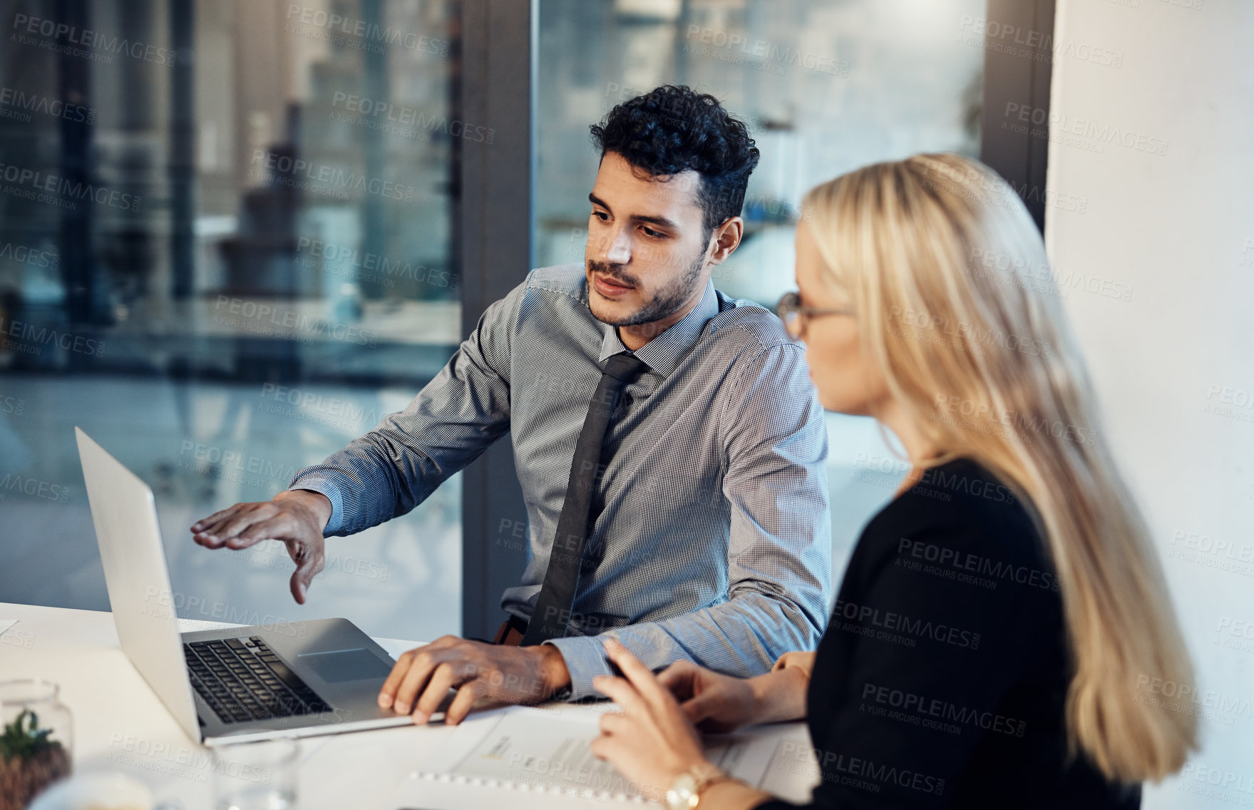 Buy stock photo Shot of a young businessman and businesswoman using a laptop together during a meeting in a modern office