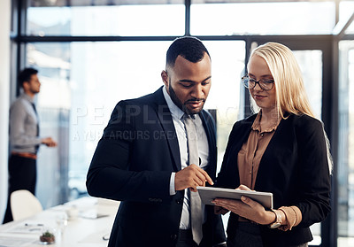 Buy stock photo Shot of a young businessman and businesswoman using a digital tablet together in the boardroom of a modern office