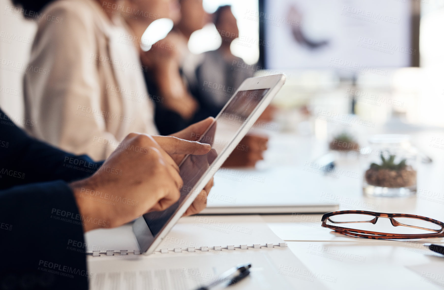 Buy stock photo Cropped shot of a businesswoman using a digital tablet during a meeting in the boardroom of a modern office