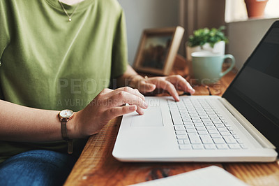 Buy stock photo Cropped shot of an unrecognizable businesswoman sitting alone in her home office and typing on her laptop