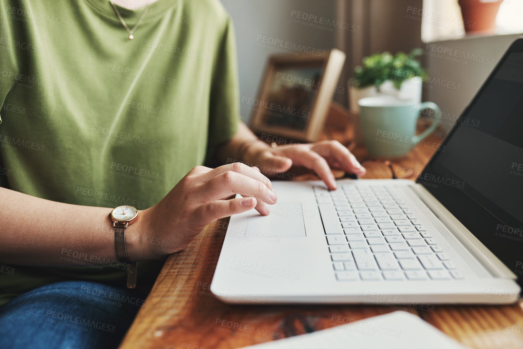 Buy stock photo Cropped shot of an unrecognizable businesswoman sitting alone in her home office and typing on her laptop