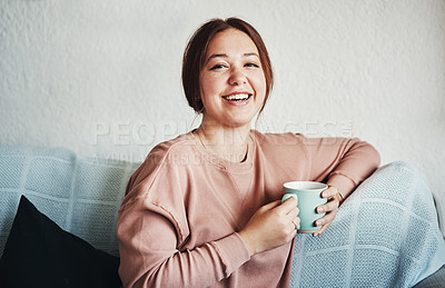 Buy stock photo Cropped portrait of an attractive young woman sitting on her sofa alone and holding a cup of coffee at home