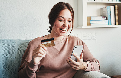 Buy stock photo Cropped shot of an attractive young woman sitting on her home sofa alone and using her cellphone for online shopping